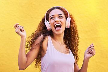 Image showing Music, idea and dance with a black woman listening to the radio outdoor on a yellow wall background. Headphones, energy and face with an attractive young female streaming audio sound for fun