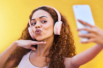 Image showing Selfie, black woman and headphones for listening to music on yellow wall background. Face of happy gen z person pout lips with curly hair outdoor while streaming audio for influencer post in Colombia