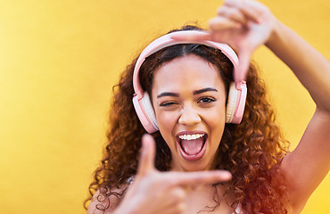 Image showing Hands, frame and portrait of woman with headphones on yellow background for profile picture. Face, female and finger framing with music for perspective, selfie and vision of happiness, smile and tech