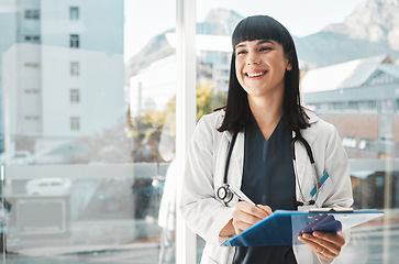 Image showing Woman, doctor and smile writing on clipboard by window for healthcare planning, strategy or notes. Happy female medical expert smiling with paperwork, prescription or medicare details at hospital