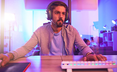 Image showing Computer video game, man and headphones for esports, online games or virtual competition in dark room. Gamer guy, digital gaming and live streaming on headset in neon lighting, tech or media streamer