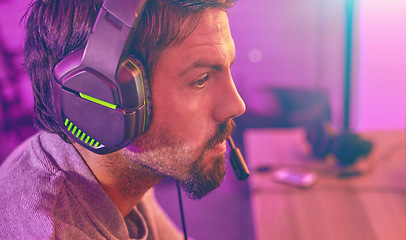 Image showing Serious face, gamer or man with headphone focus on online competition, tournament or gaming in room. Neon, thinking or male geek for live internet stream, esports challenge or video game at night