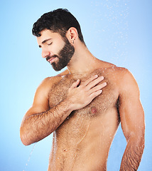 Image showing Body care, shower and man in studio for wellness, hygiene and skincare against blue background. Cleaning, chest and male model relax in luxury, water splash and beauty routine isolated in a bathroom