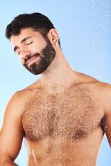 Image showing Body care, relax and man in studio for skincare, grooming and hygiene against blue background. Luxury, bathroom and guy model happy in shower, smile and isolated on water splash, cosmetic or wellness