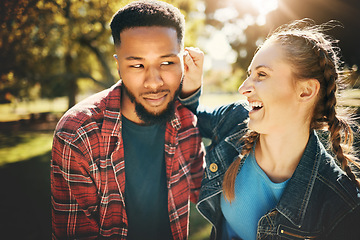 Image showing Interracial couple, laughing and smile in nature for playful love, bonding and funny relationship. Happy woman holding man ear with laugh for fun loving care, affection or playing in a park outdoors