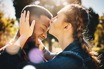 Image showing Interracial couple, forehead kiss and smile in nature for love, bonding and embracing relationship. Happy woman kissing man on head smiling for loving care, affection or embrace in a park outdoors