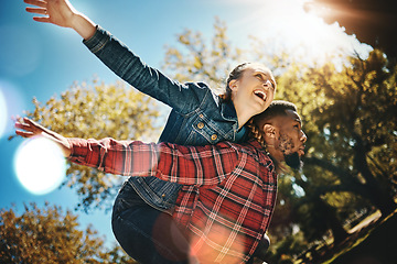 Image showing Young couple, flying and piggyback in park, summer and date together in sunshine, happiness or nature. Happy man carrying woman in garden of love, care and freedom to play, smile or diversity partner