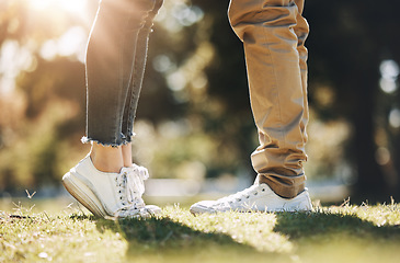 Image showing Couple, legs and feet standing on grass field for love, affection or bonding together in nature. Leg of woman raising foot for height with man for loving care, touch or embrace in the park outdoors