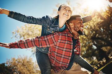 Image showing Happy couple, flying arms and piggyback in park, summer and date together in sunshine, happiness and support. Below of man carrying woman in garden for love, care and freedom with diversity partner