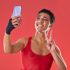 Image showing Selfie, queer and gay man peace sign gesture for social media update isolated against a studio red background. LGBTQ, non binary and gen z fashion model with online photo for the internet