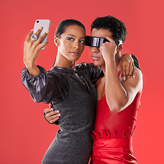 Image showing Selfie, fashion and funky people isolated on red background for queer, creative gen z and cyberpunk aesthetic. Futuristic glasses, profile picture and beauty couple of friends, model or youth makeup