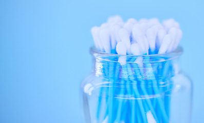 Image showing Glass container with cotton makeup cosmetic swab buds, self cleaning ear canal and environment recycle. Covid nasal test, skincare health safety and climate change on blue background closeup