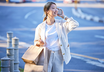 Image showing Phone call, shopping bag and Asian woman with mobile mockup screen by a city street. Retail customer, conversation and happiness of a young person with paper bags from shop sale or store discount