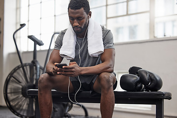 Image showing Phone, music and fitness with a black man taking a break in a gym during his boxing workout. Exercise, social media or sports app with a male boxer or athlete tracking progress and resting on a bench