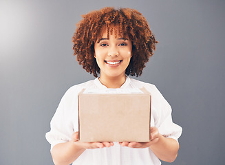 Image showing Portrait, box and delivery with a black woman courier holding cardboard in studio on a gray background. Stock, supply chain and shipping with an attractive young female indoor to deliver goods