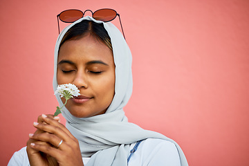 Image showing Smelling, fresh and Muslim girl with a flower isolated on a pink background in a studio. Spring, peace and Islamic woman with the aroma of a calming plant for relaxation, stress relief and summer