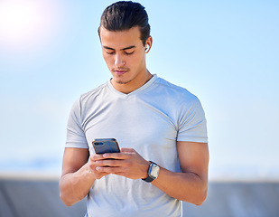 Image showing Phone, fitness and man texting on social media or streaming music online during morning exercise or workout routine. Person, web and athlete using a mobile training app or website to track health