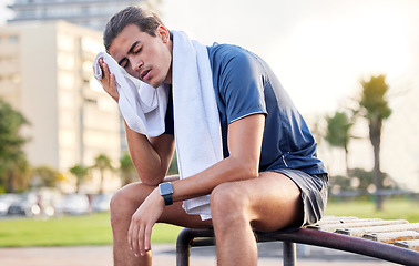 Image showing Fitness, exercise and tired man with a towel on park bench to relax or rest after running for cardio. Sports person with fatigue and sweating outdoor post workout or training for health and wellness