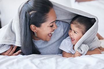 Image showing Mother, parent and baby playing or bonding in a bed with blanket laughing being funny together in a bedroom or room. Mom, kid and single mum in a home or house with little daughter or child