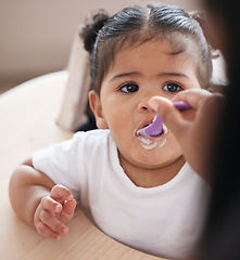 Image showing Baby, food and hand feeding with spoon while eating for nutrition, development and growth in a chair. Face of girl toddler or child having breakfast, lunch or dinner while hungry in family home