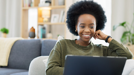 Image showing Laughing afro woman using laptop to watch funny, comedy movies or videos. Smiling, happy woman with stylish, funky and cool hair sitting alone on home living room sofa, relaxing and using technology