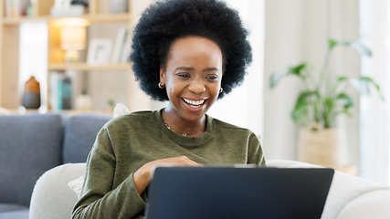 Image showing Female with an afro enjoying a comedy movie on her laptop while eating a big bowl of popcorn at home. African woman laughing while watching funny movies on her couch. Young lady streaming online