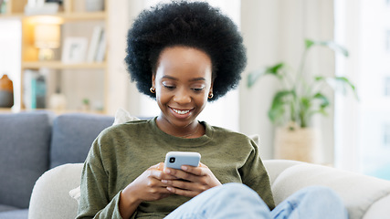 Image showing Young woman smiling and laughing while texting on a phone at home. Cheerful female chatting to her friends with apps, scrolling social media and watching funny internet memes while relaxing on a sofa