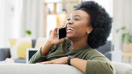 Image showing Happy African woman talking on the phone while relaxing on her cozy sofa at home. Cheerful black female with afro laughing while having a pleasant and funny conversation with a friend on her mobile