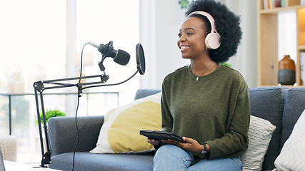 Image showing Cool afro journalist using digital tablet, talking into microphone and hosting podcast or broadcasting news while wearing headphones. Excited young woman using technology to promote on air from home