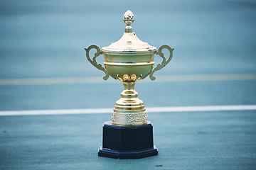 Image showing Trophy, award and target with a sports cup on an empty court outdoor for the winner, champion or victor. Gold, goal and success with a prize on the floor outside at a stadium or arena for sport