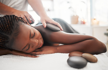 Image showing Black woman, hot stone massage, spa with hands of masseuse, holistic and wellness with treatment. Health, peace of mind and zen, self care and rocks, stress relief for people and back skin detox