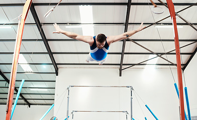 Image showing Man, acrobat and gymnast flying off rings in fitness for practice, training or workout at gym. Professional male in gymnastics or performance for athletics, acrobatic or strength and balance exercise