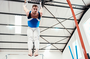 Image showing Man, acrobat and gymnastics balance on rings in fitness for practice, training or workout at gym. Professional male gymnast hanging on ring circles for athletics, acrobatics or strength exercise