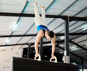 Image showing Man, acrobat and gymnastics upside down in balance for fitness practice, training or workout at gym. Professional male gymnast holding up body weight in pommel horse, athletics or strength exercise