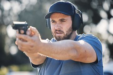 Image showing Man, gun and learning to aim at shooting range outdoor for security target training. Face of person train with safety gear headphones for focus on sport competition with firearm weapon in hands