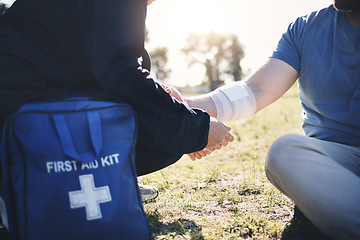 Image showing First aid, help and arm injury by man with medic on the ground during morning cardio outdoors. Medical, emergency service and injured male with bandage on a field after exercise, workout or walk