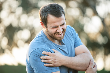 Image showing Man, fitness and injury or shoulder pain in park while running, exercise or training accident with muscle. Sport, guy and injured arm by runner in nature for cardio workout while suffering arthritis