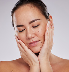 Image showing Beauty, face and skincare of woman in studio for cosmetics, dermatology and glow. Aesthetic asian model person with hands on skin for makeup, mole and facial self care for wellness on grey background