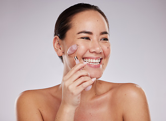 Image showing Face skincare, beauty and Asian woman with jade roller in studio isolated on gray background. Dermatology aesthetics, thinking or happy female model with rose quartz stone or crystal for skin health.