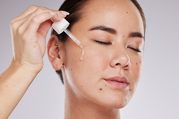 Image showing Eyes closed, face and skincare of woman with serum in studio isolated on a gray background. Dermatology skin, beauty cosmetics and female model apply hyaluronic acid, essential oil or retinol product