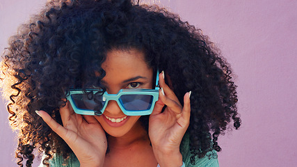 Image showing Black woman with sunglasses, smile, laugh and play with hair against pink backdrop in sunshine. Model girl with curly afro hair, happy with blue fashion glasses against pink wall or background