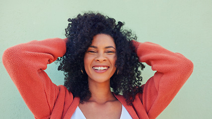 Image showing Freedom, hair and fun with a young woman playing with her curly hairstyle and laughing on a green wall background. Happy, funny and smile with an attractive and playful young female feeling carefree