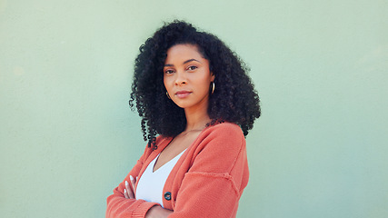 Image showing Black woman, confident beauty and young model pose for portrait with afro hair on green background. African girl in orange sweater, fold arms with cool serious face and casual fashion lifestyle