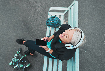 Image showing Phone, happy and woman roller skating with music for training, exercise and fun on a city bench. Laughing, mobile and above of a mature lady listening to a podcast while ready to start a skate