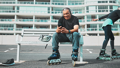 Image showing Fitness, roller blade and senior man with smartphone, smile and guy on bench, headphones and relax. Exercise, mature male and gentleman outdoor, skater and cellphone for social media, music and break