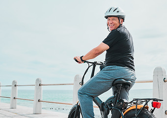 Image showing Electric bike, portrait or travel with a senior man on a promenade, riding eco friendly transport by the beach. Sustainability, cycling or mock up with a mature male tourist by the seaside for a ride