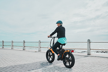 Image showing Mature woman, helmet or electrical bike by beach for future fitness, clean energy transport or sustainability travel. Old person, ebike or electric bicycle with head safety for eco friendly cycling