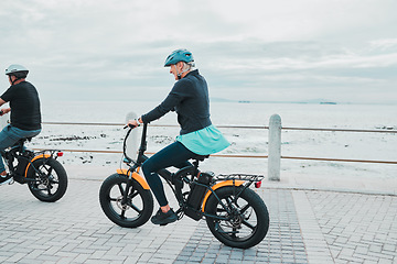 Image showing Couple, helmet or electrical bike by beach, ocean or sea in future transport, clean energy or sustainability travel. Technology, electric or eco friendly bicycle for happy woman or mature cycling man