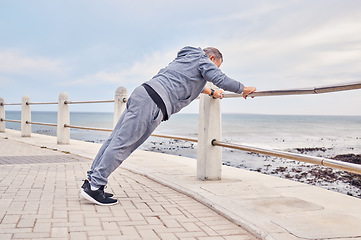 Image showing Senior man, fitness and stretching at beach sidewalk for energy, wellness and healthy cardio workout. Elderly male, warm up and exercise at seaside promenade for training, sports and body performance