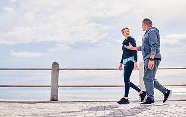 Image showing Walking, fitness and senior couple talking by ocean for exercise, healthy body and wellness in retirement. Sports, nature and elderly man and woman for warm up, cardio workout and training outdoors